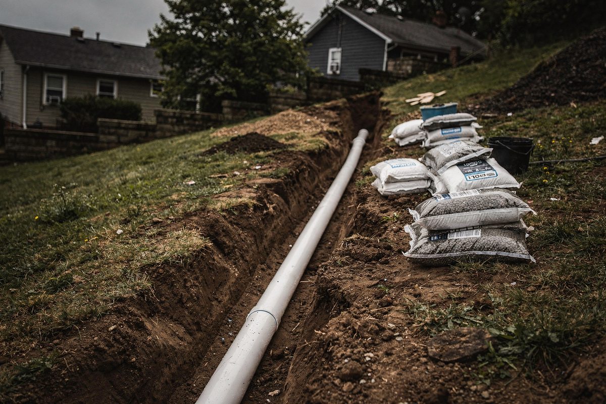 Open drainage trench with solid pipe laid along a sloped hillside yard